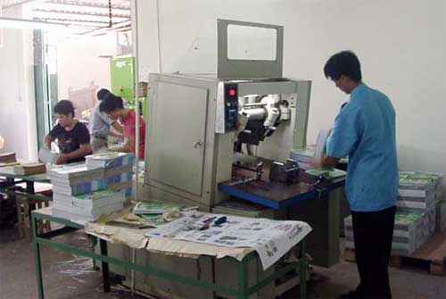 工人用三面切書機(jī)裁切書刊